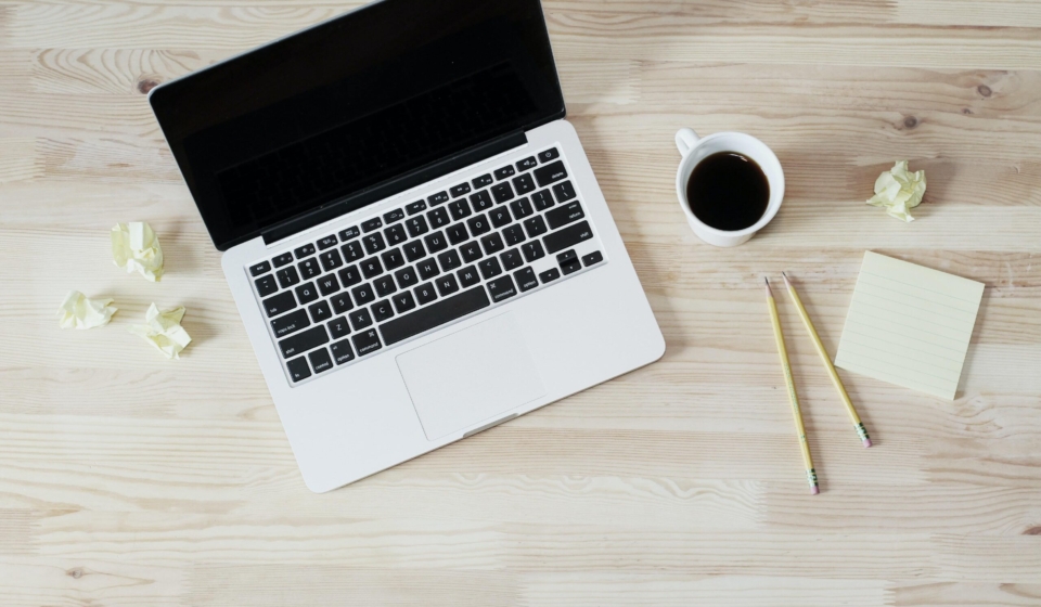 Laptop with cup of coffee and a few sheet of paper