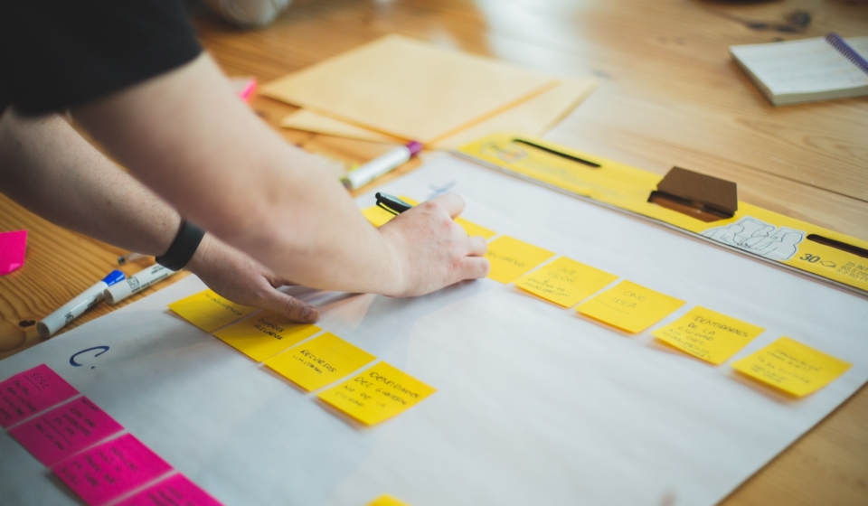 people writing notes on papers of different colors on a big desk