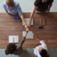 four people crossing their hands over a desk